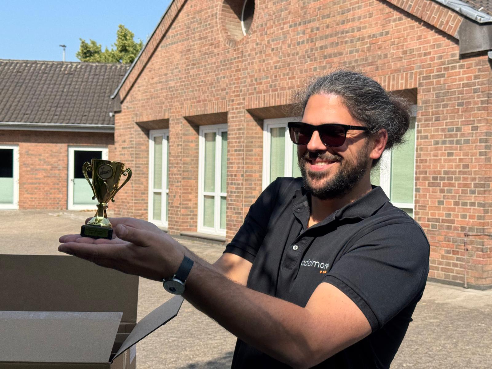 addmore-Mitarbeiter Riccardo präsentiert den Pokal des addmore Familienlaufes